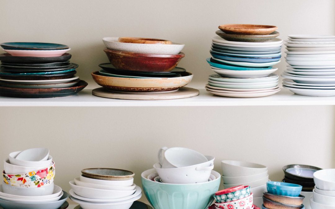 Stacks of mismatched plates and bowls on two shelves